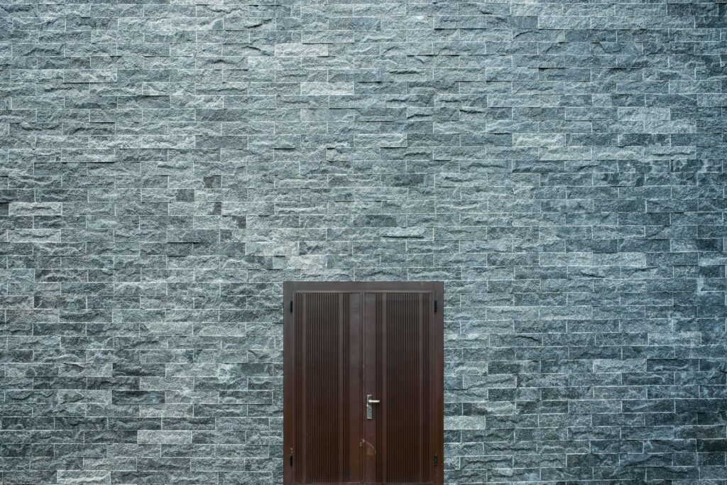 A grey slate wall with a dark timber door