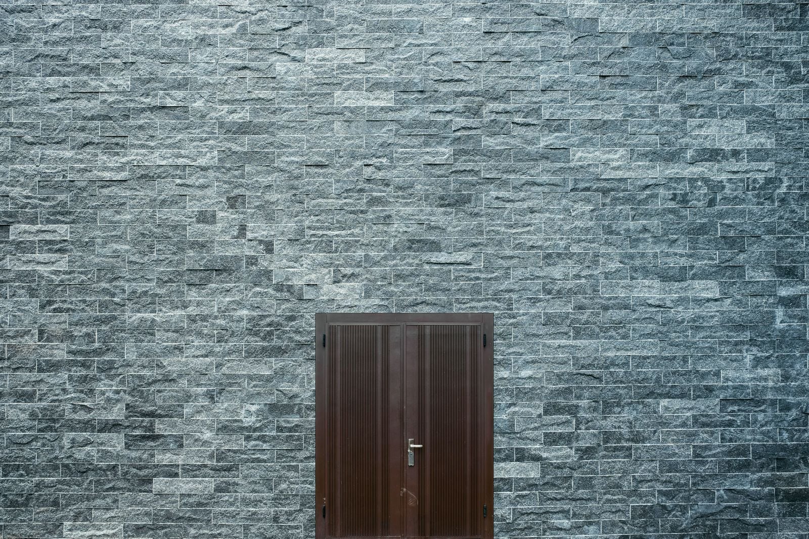 A grey slate wall with a dark timber door