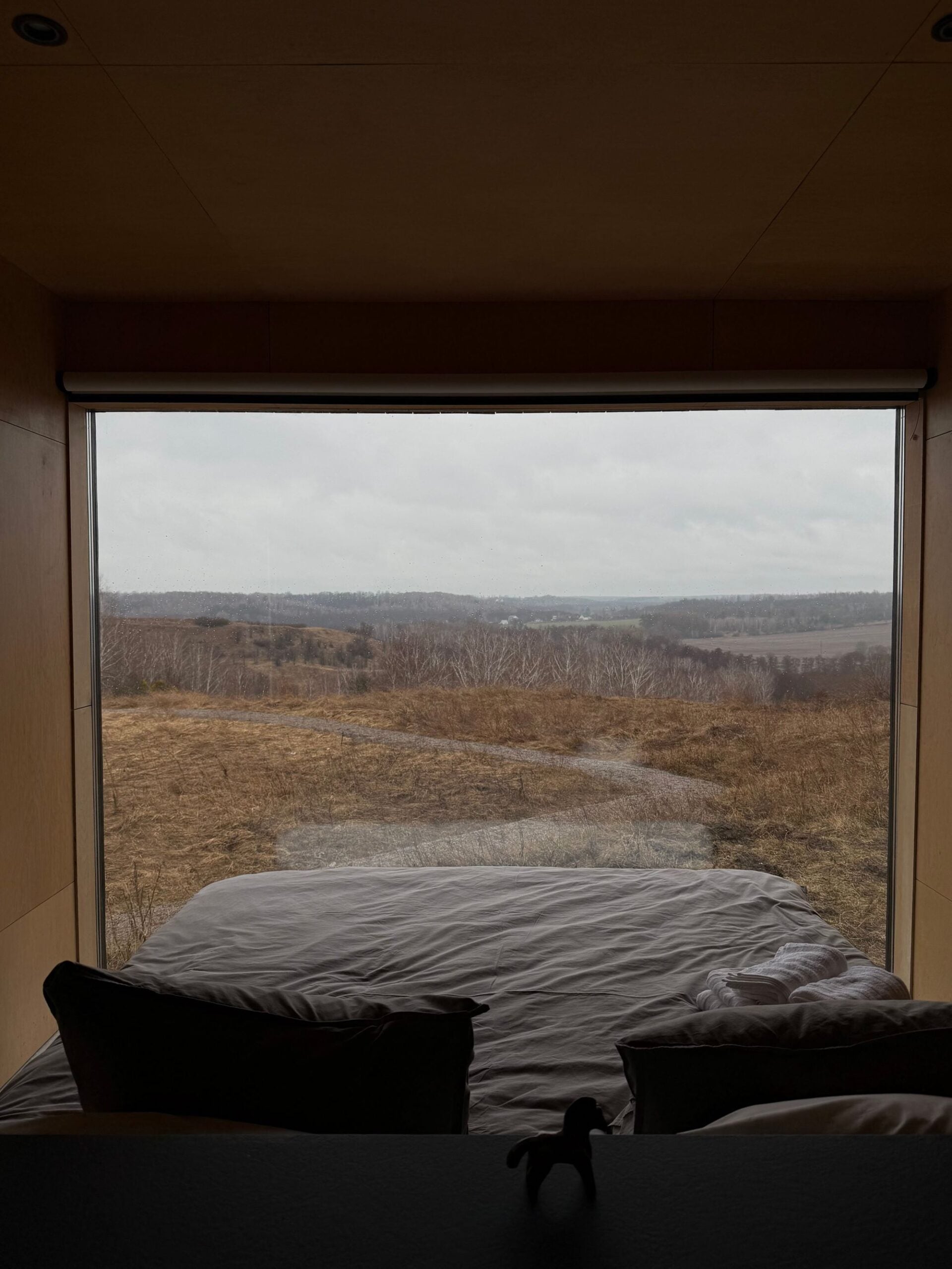 A bed facing a wide window onto brown moorland