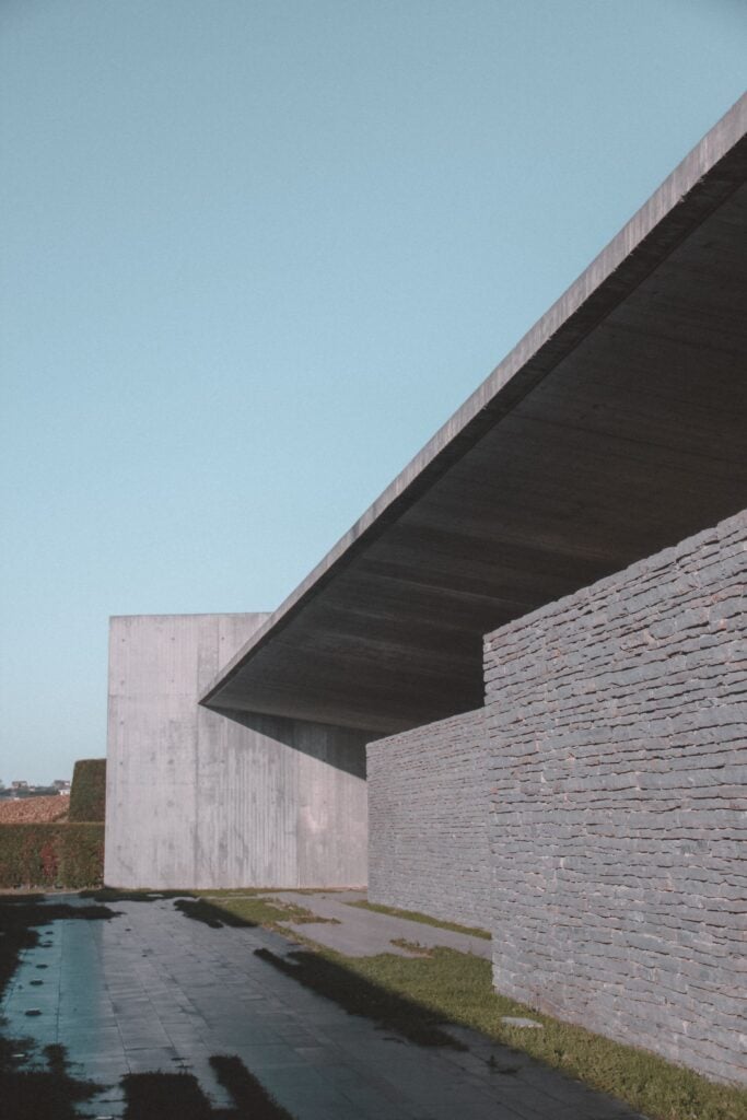 A cantilevered concrete roof over a long stone wall
