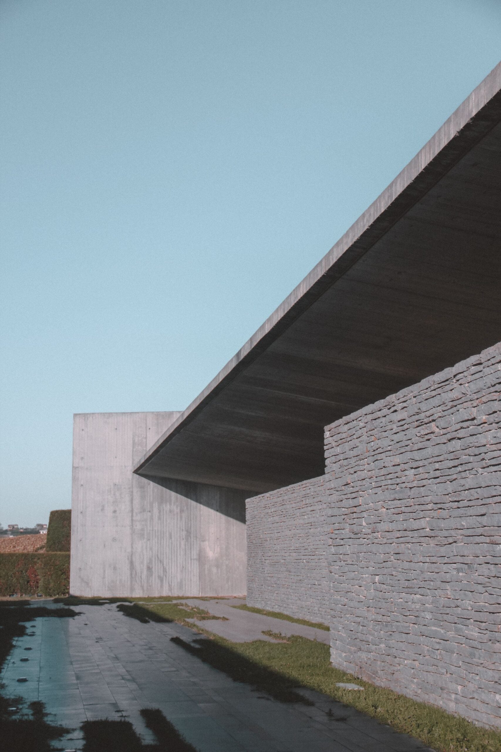 A cantilevered concrete roof over a long stone wall