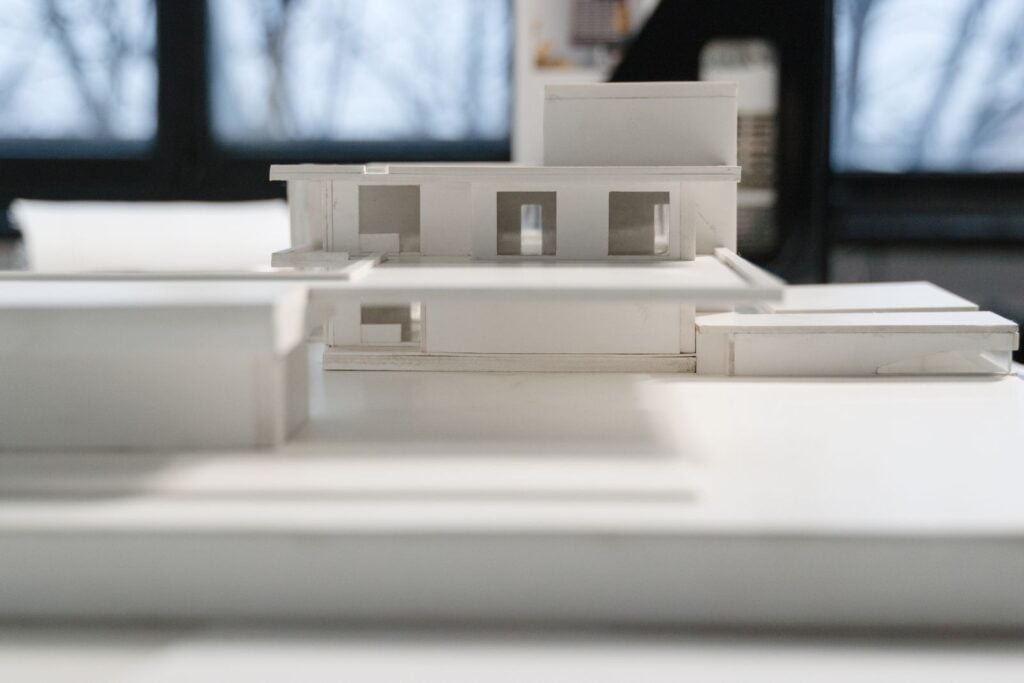 A white card model of a house on a table