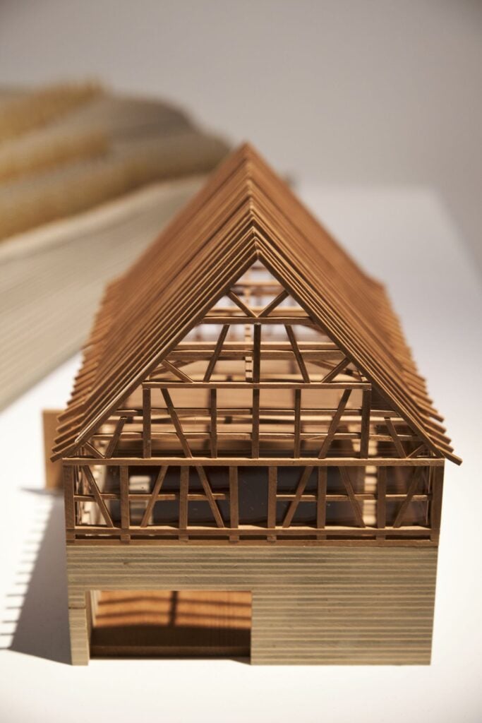 A timber frame roof model on a workbench