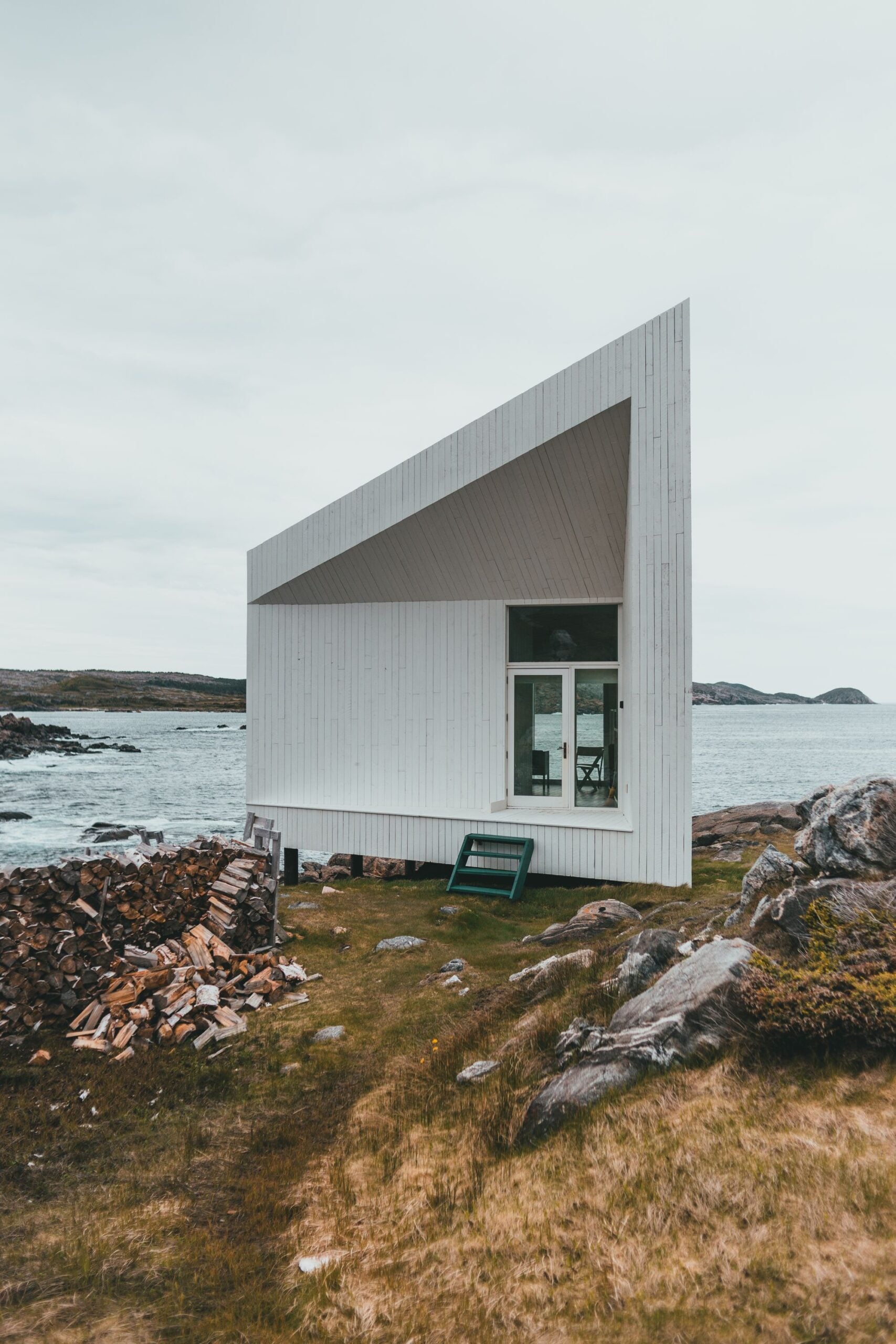 Havhuset seen from the side, a white tilted volume on the rocks with the sea behind