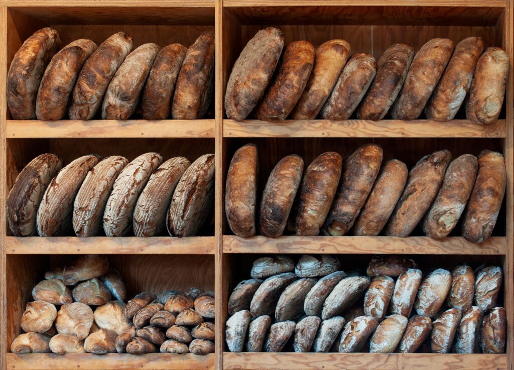 Wooden shelves stacked with sourdough loaves