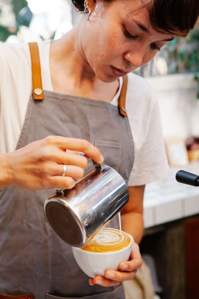 Barista in an apron pouring latte art