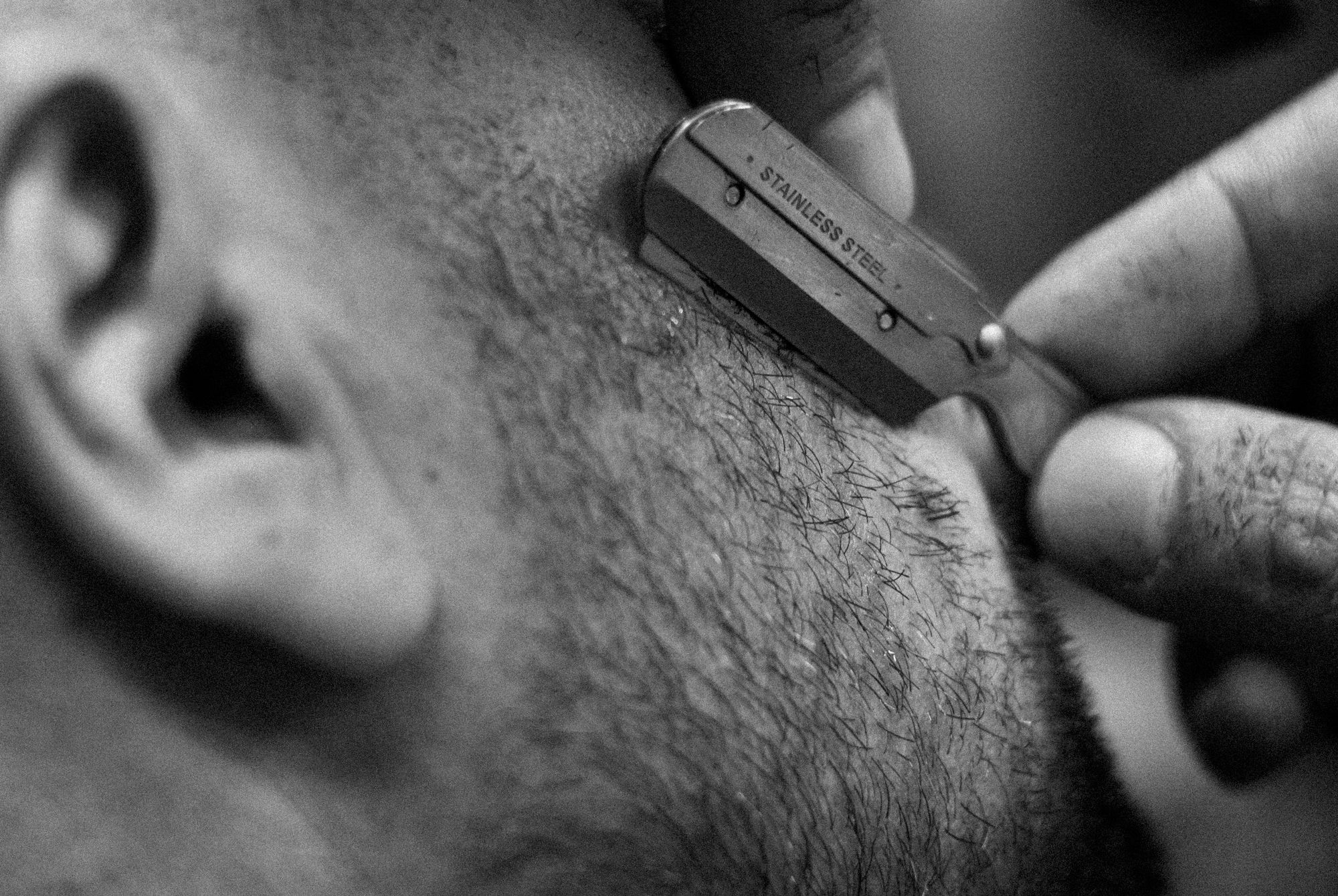 Close up of a straight razor tidying a neckline, black and white