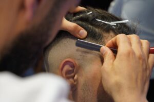 Barber cutting a hard part into a fade with a razor