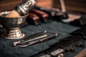 Shaving bowl, brush, razors and combs laid out on a dark towel