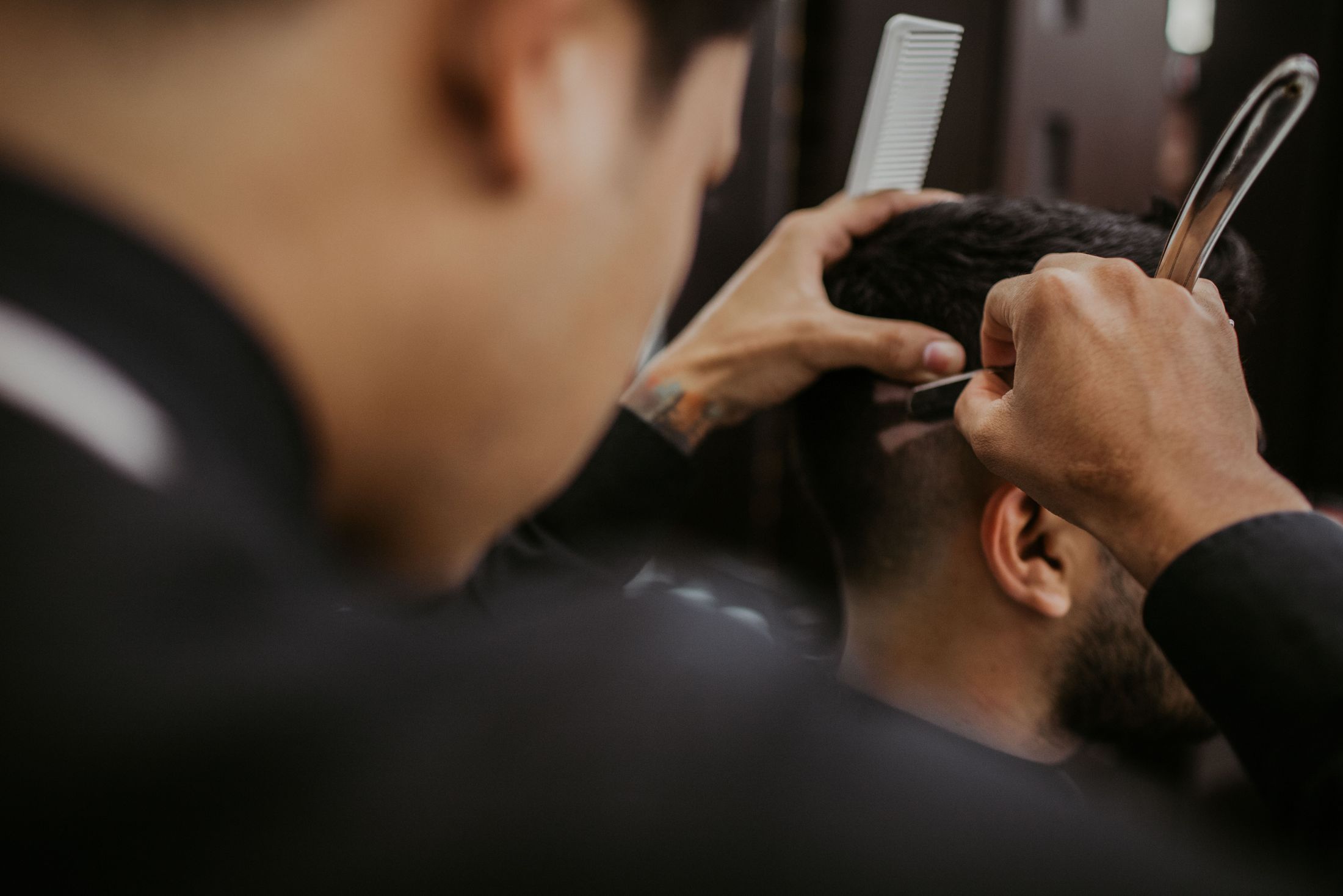 Barber working on a client's hairline with a comb and razor