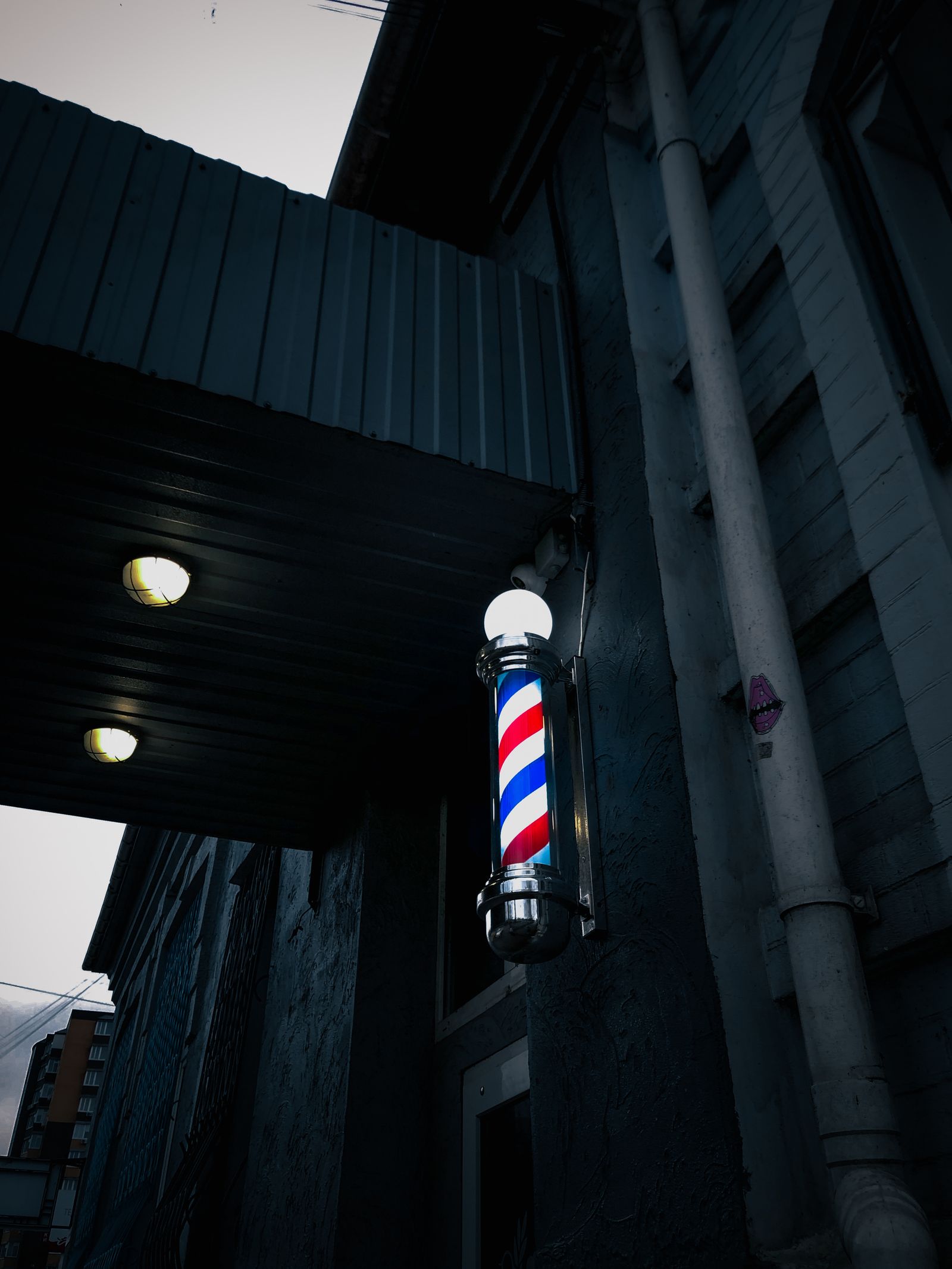 Barber pole on a dark storefront at dusk