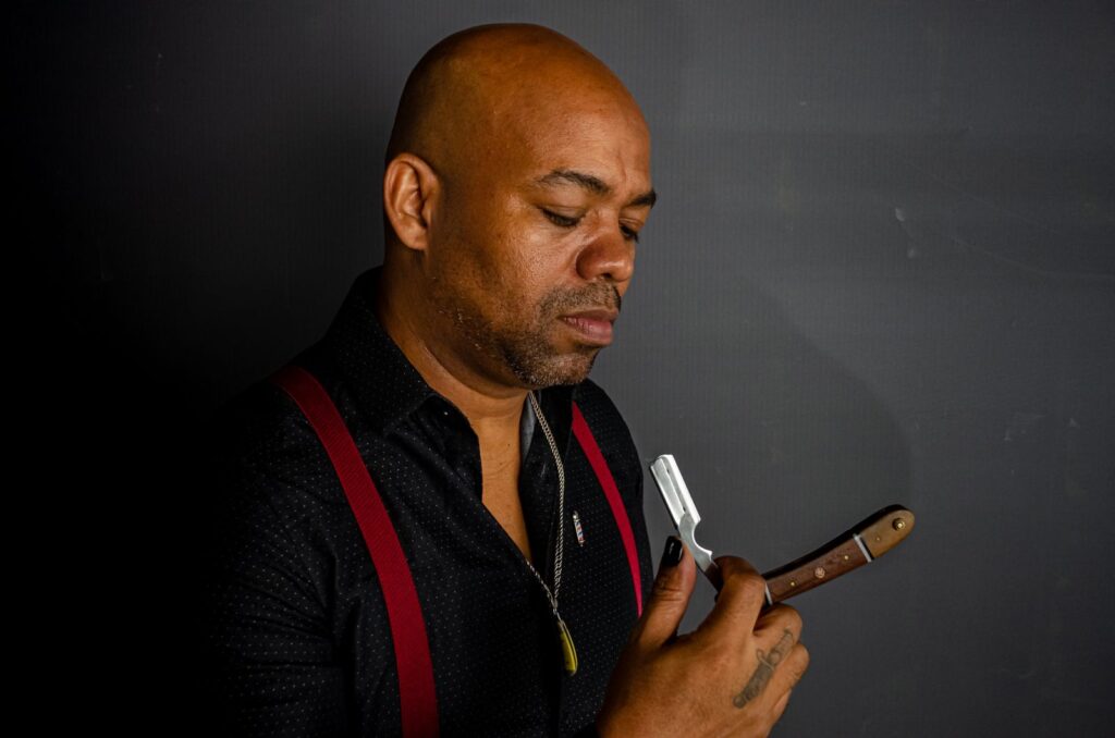 Portrait of a barber in suspenders holding a straight razor