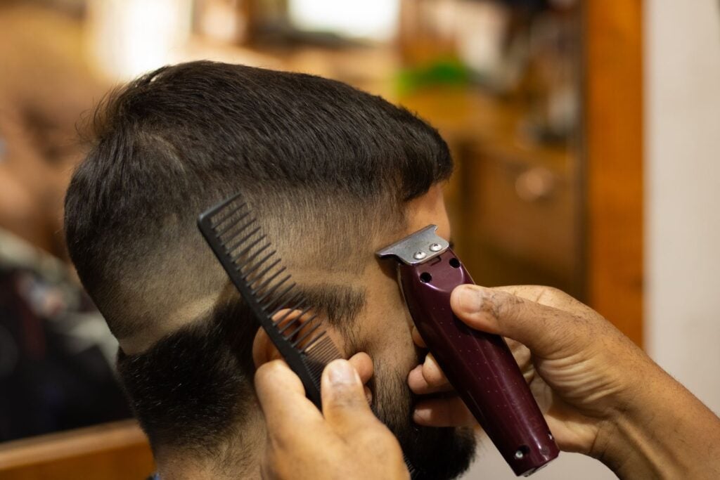 Barber shaping a fade with a trimmer and comb