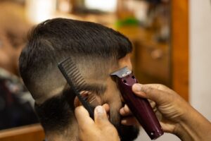 Barber shaping a fade with a trimmer and comb