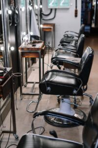 Black barber chairs lined up along mirrored stations