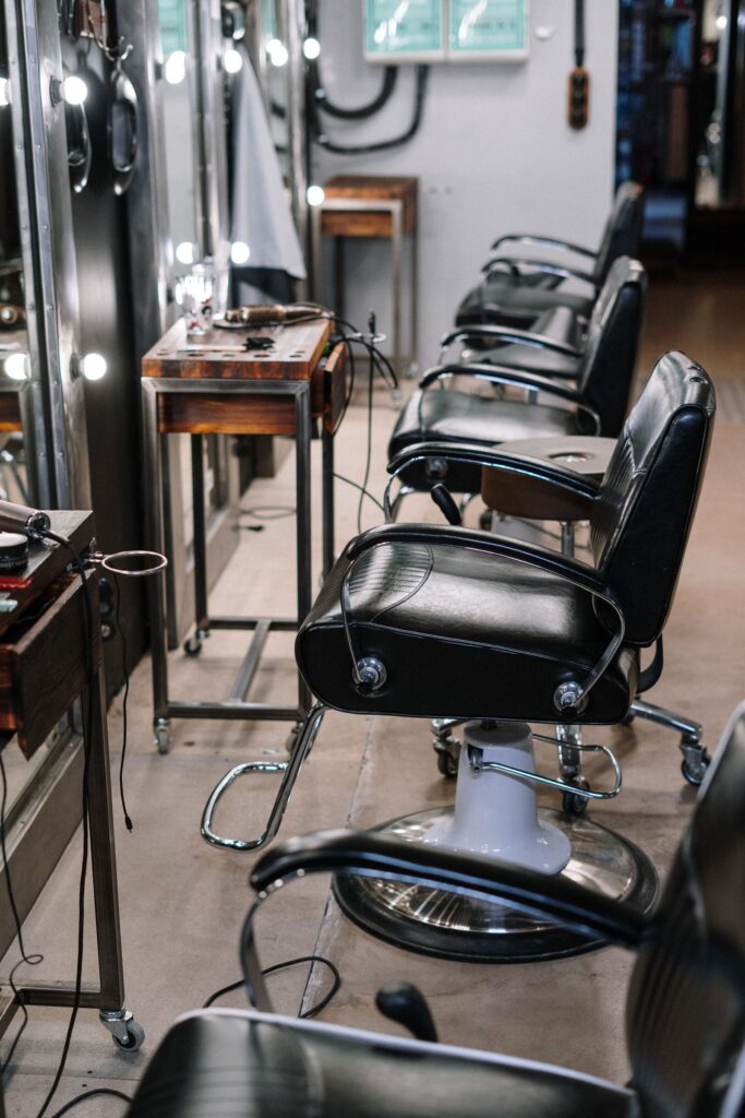 Black barber chairs lined up along mirrored stations