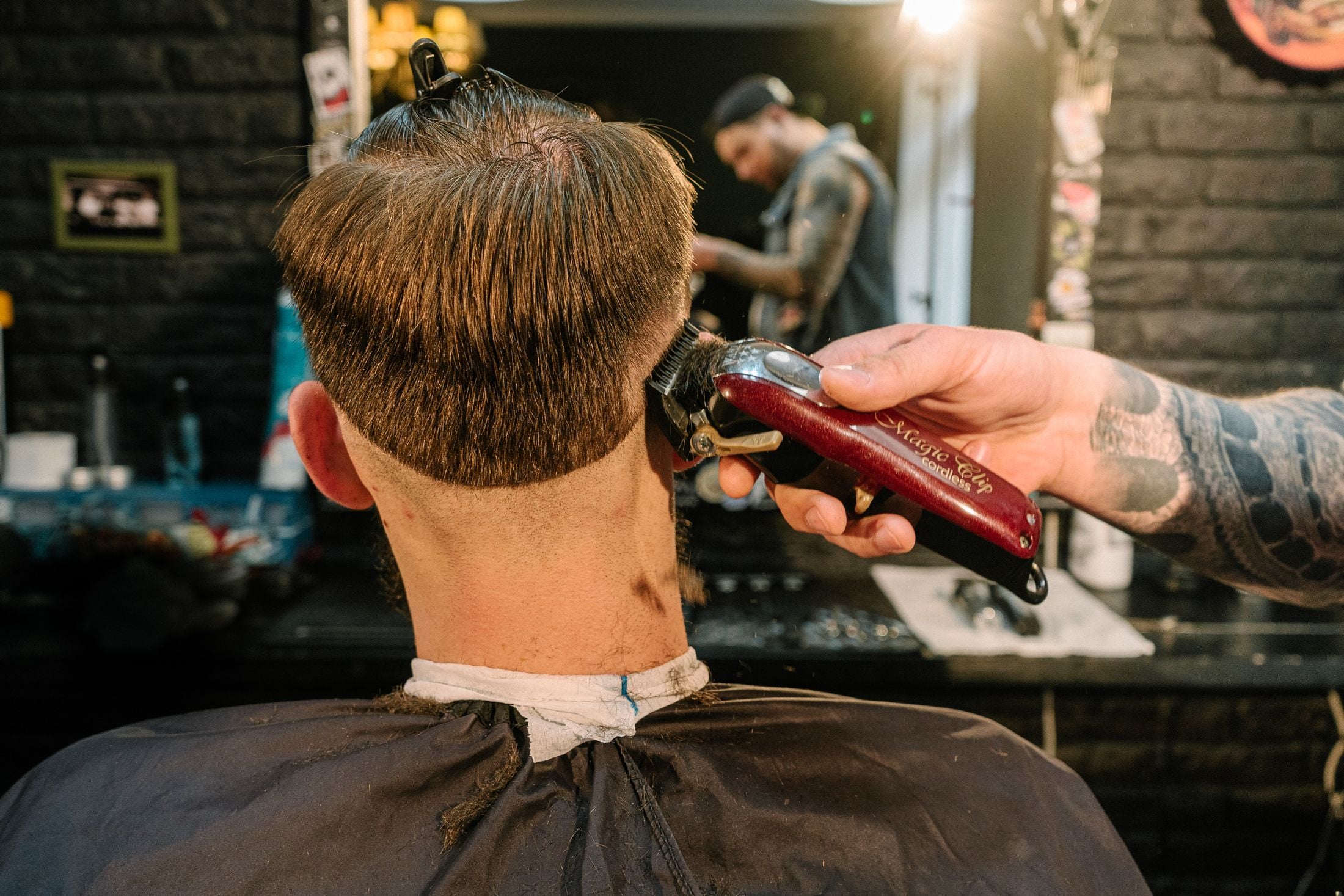 Barber tapering the back of a client's haircut with a red clipper