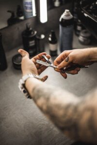Tattooed barber's hands holding scissors over the shop floor