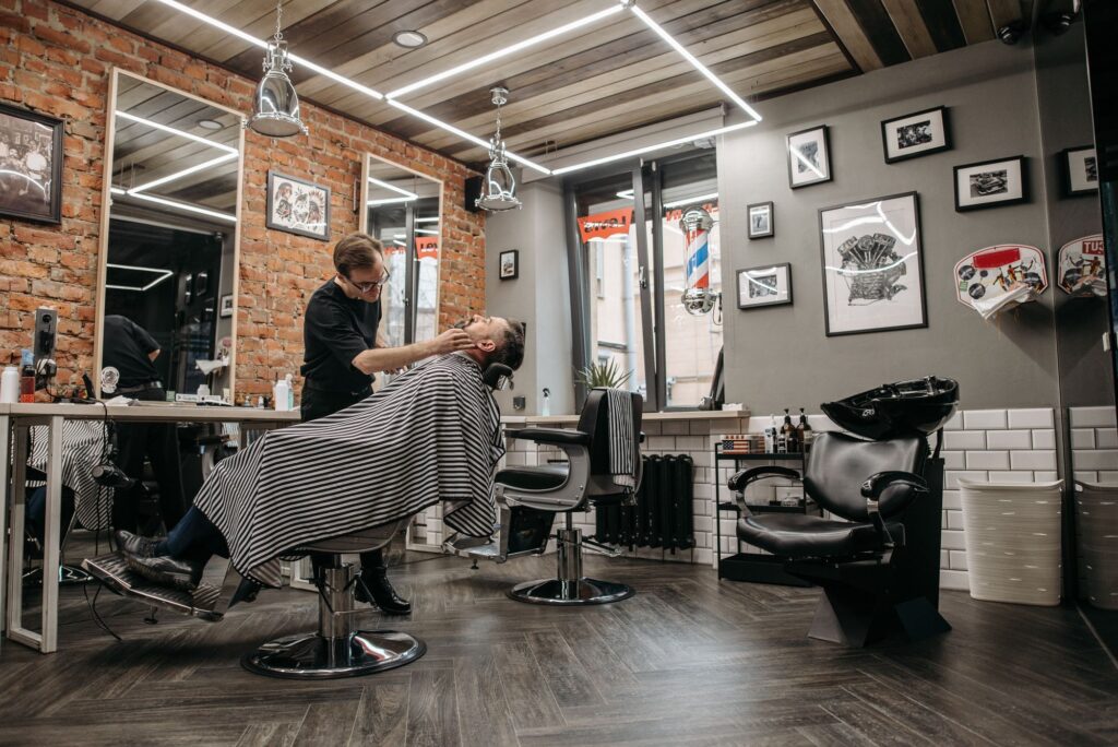 Barbershop interior with brick walls, chairs and a barber at work