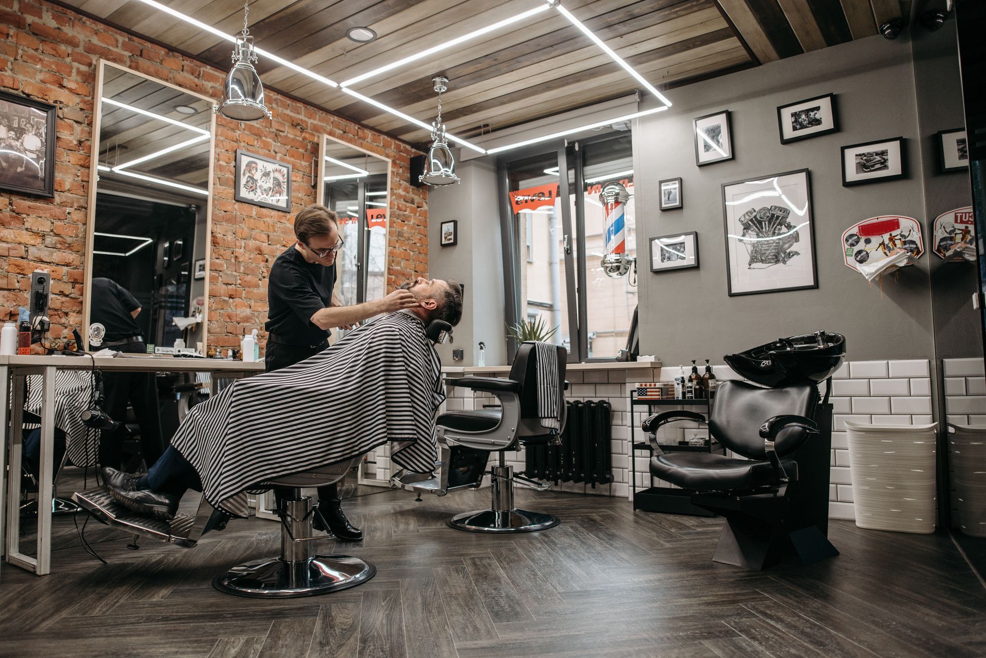 Barbershop interior with brick walls, chairs and a barber at work