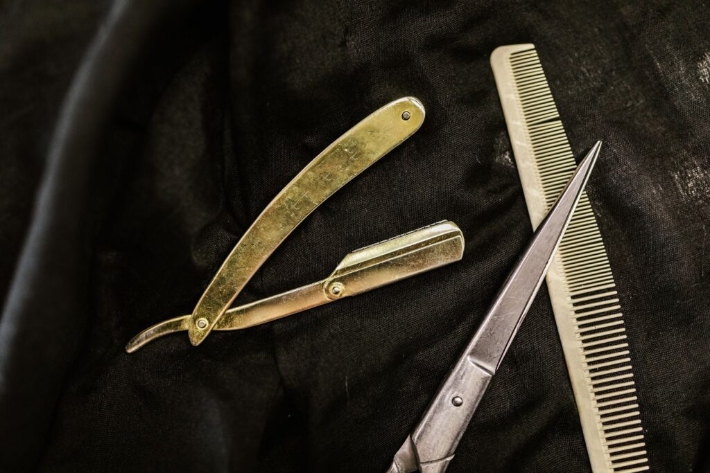 Brass straight razor, scissors and comb on black leather
