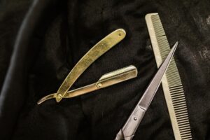 Brass straight razor, scissors and comb on black leather
