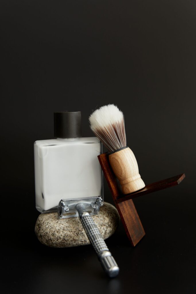 Aftershave bottle, shaving brush and safety razor on a stone