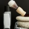 Aftershave bottle and brush resting on stacked stones