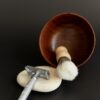 Walnut shaving bowl with a brush and a safety razor on a stone