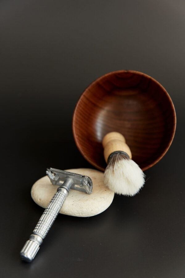 Walnut shaving bowl with a brush and a safety razor on a stone