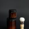 Stacked amber jars of matte clay next to a small brush