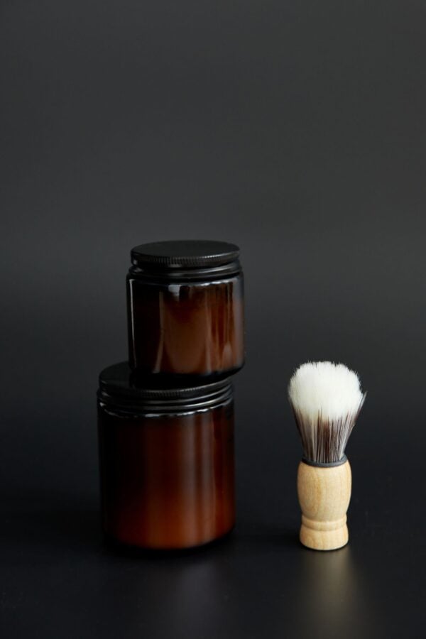 Stacked amber jars of matte clay next to a small brush