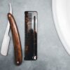 Wood handled straight razor next to a tortoiseshell pocket comb