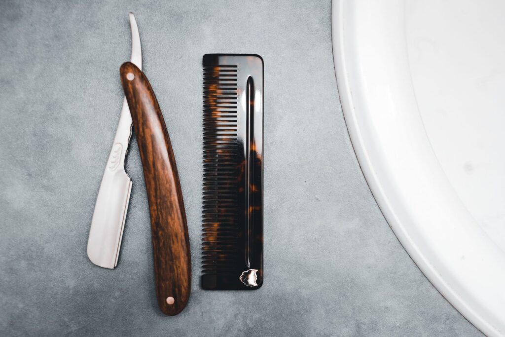 Wood handled straight razor next to a tortoiseshell pocket comb