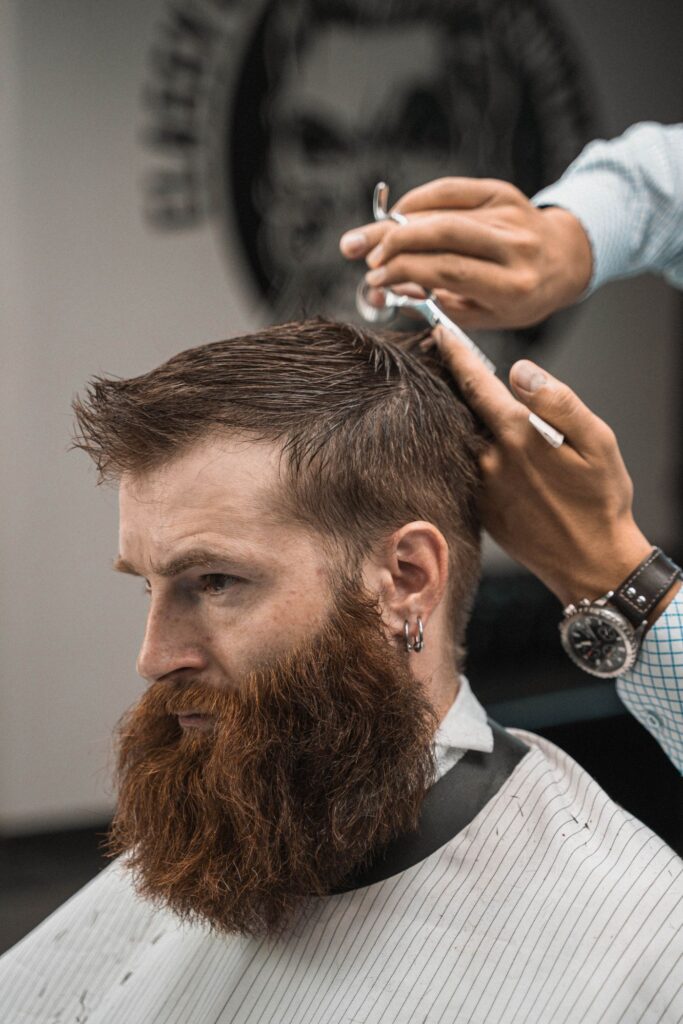 Man with a long red beard having his hair trimmed
