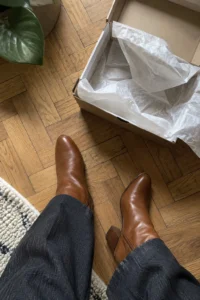 Customer top-down photo of cognac block-heel ankle boots next to the open shoe box