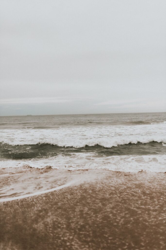 Soft waves rolling onto the shore under a pale grey sky