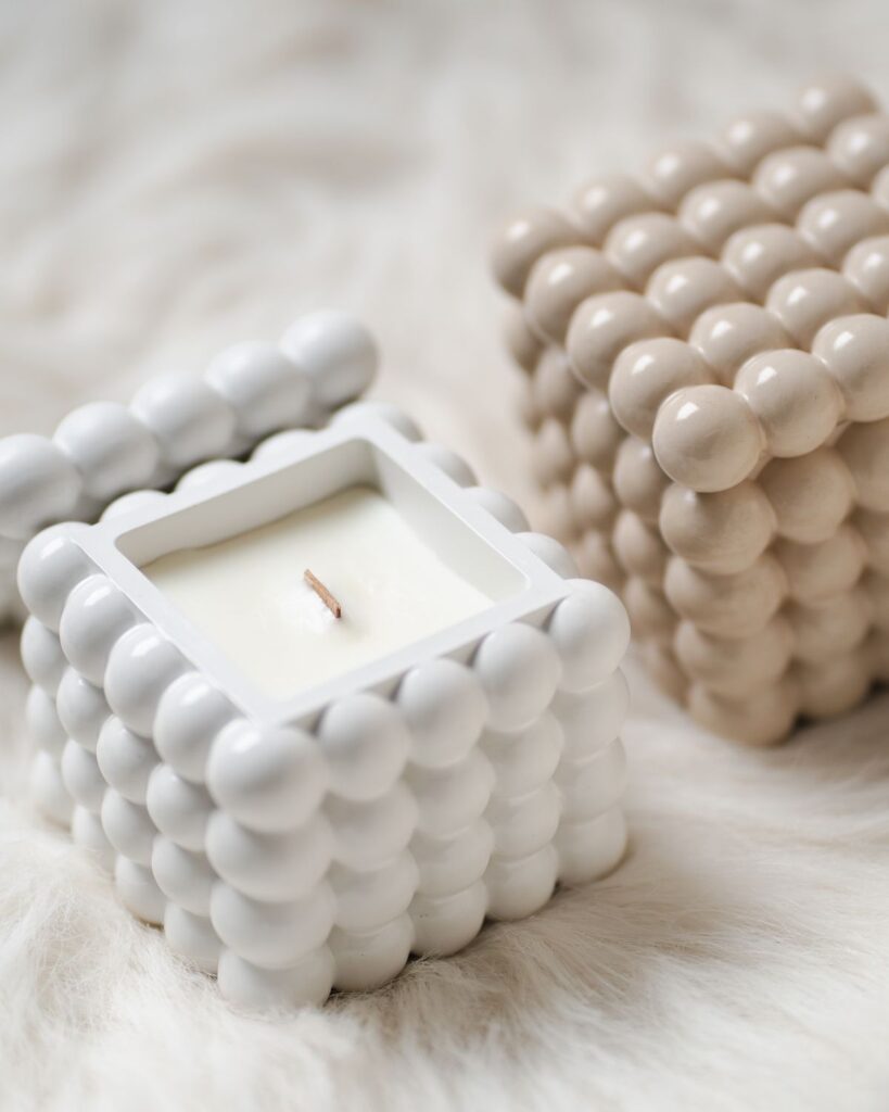 White bubble-textured ceramic candle on a fur throw
