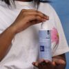 Person in a white shirt holding a body care bottle