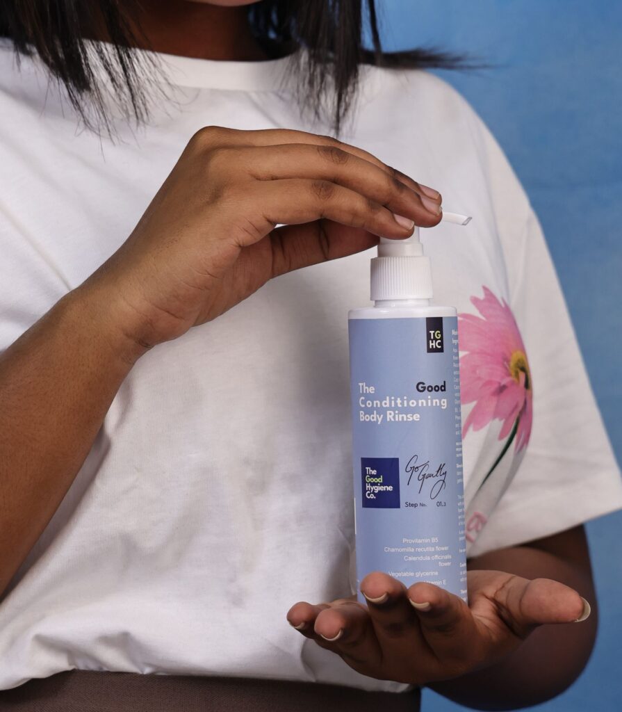 Person in a white shirt holding a body care bottle