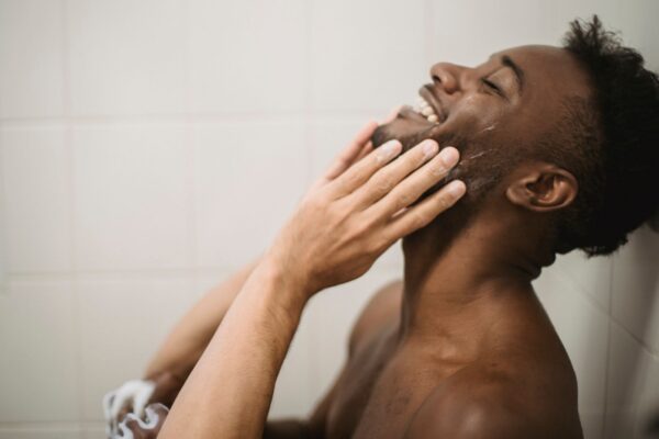 Close-up portrait of a man touching his face in a tiled bathroom