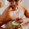 Woman applying cream to her shoulder