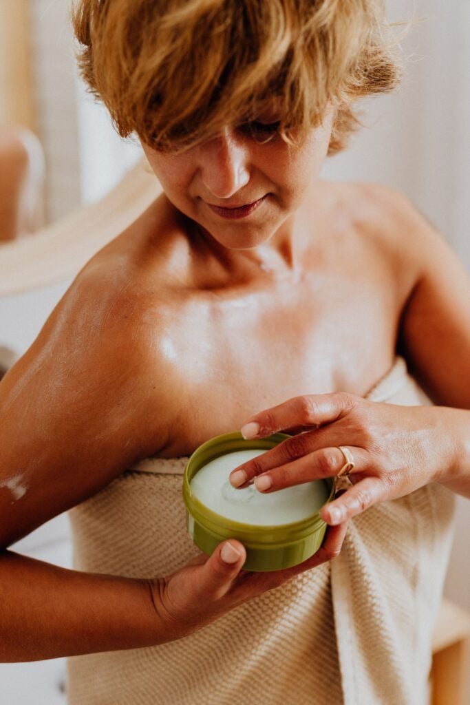 Woman applying cream to her shoulder