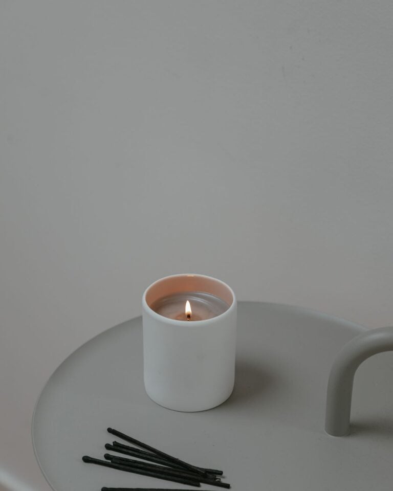 Lit white candle on a grey tray with matches