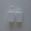 Two white pump bottles on a white surface