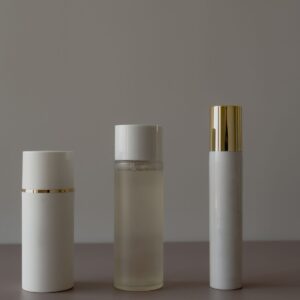 Three white bottles with gold caps on a grey surface