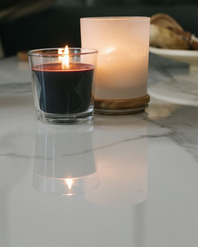 Lit candles in glass on a marble surface