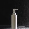 Pump bottle standing in a dark shower under falling water