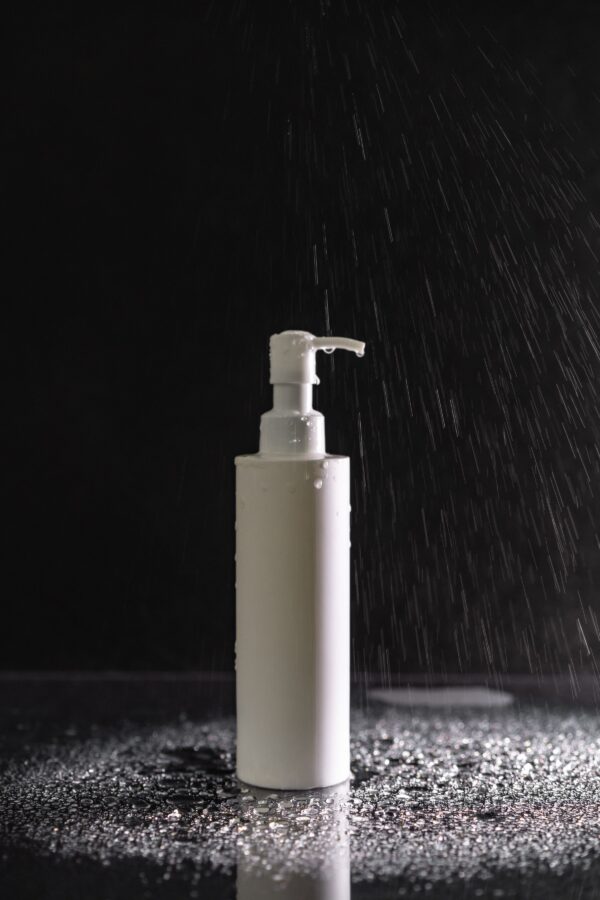 Pump bottle standing in a dark shower under falling water