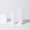 Two white cosmetic bottles on a white surface